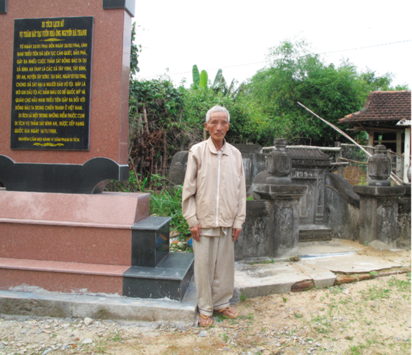 A victim standing next to the mass grave of his family members who were massacred in the Tay Vinh massacre.